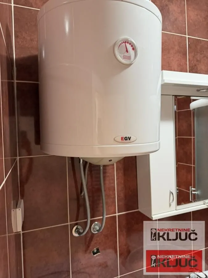 Bojler montiran na zid u kupatilu obloženom pločicama.