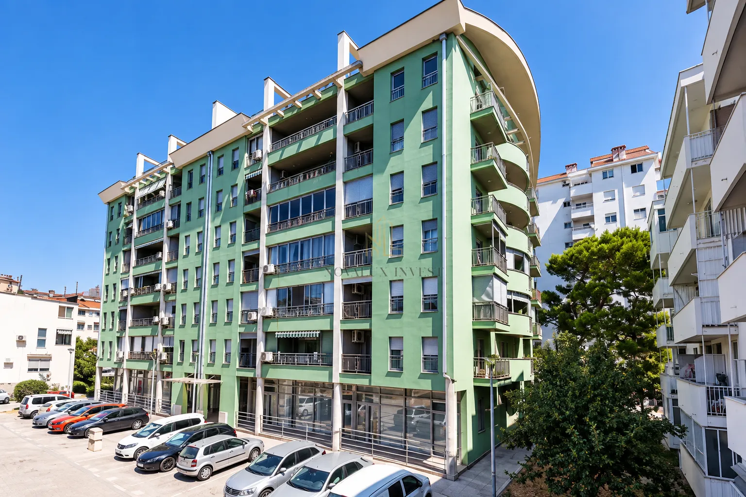 Exterior view of an apartment building with a green facade and a parking lot in the courtyard.