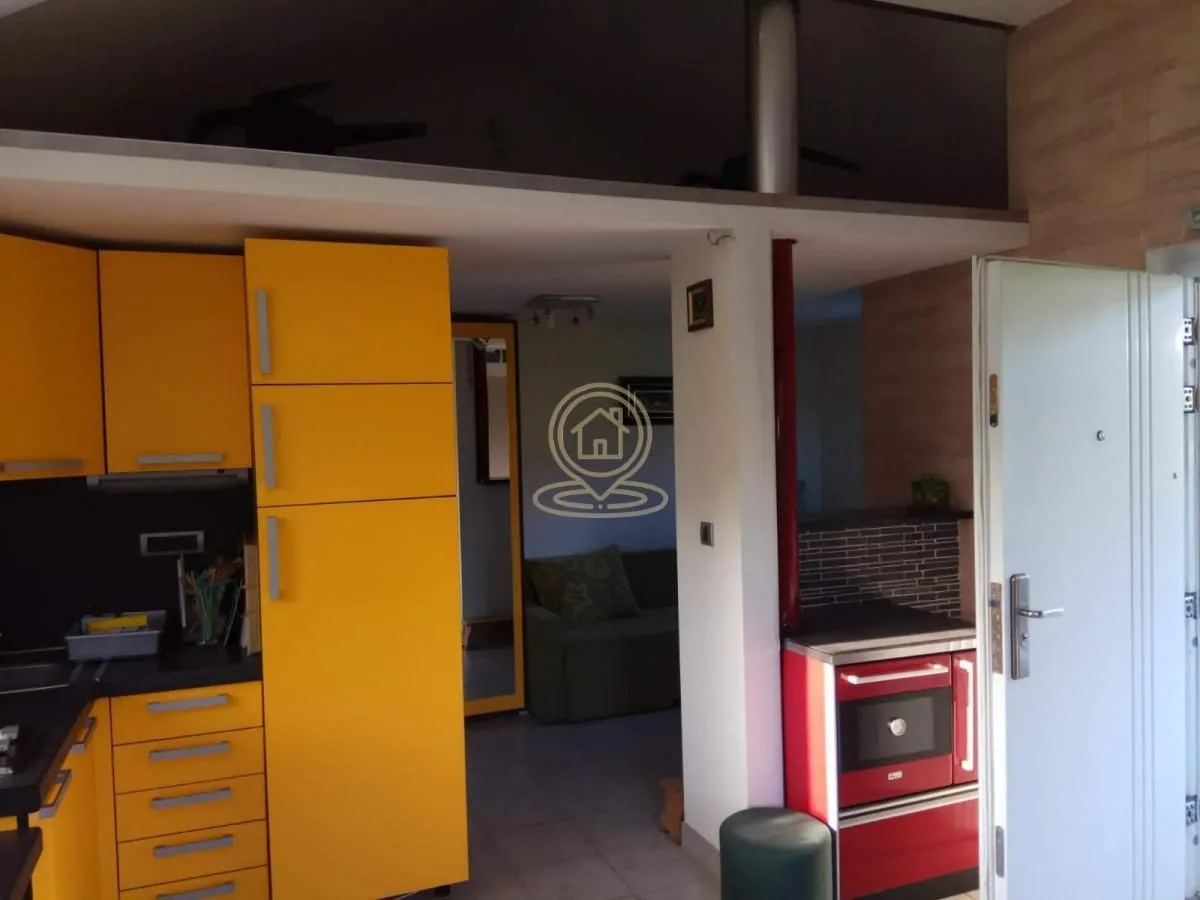 Pogled na deo kuhinje sa žutim elementima i šporetom.