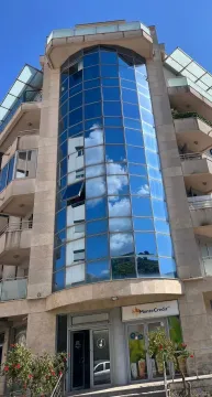 Exterior of a modern residential and commercial building with a glass facade. - image 2