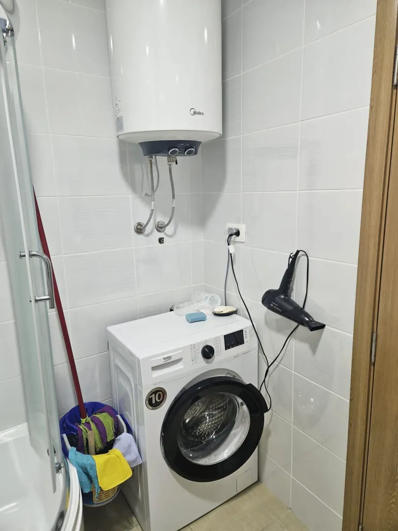 Bathroom with a shower cabin, washing machine, and water heater.
