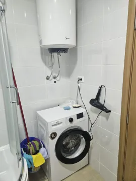 Bathroom with a shower cabin, washing machine, and water heater. - image 16