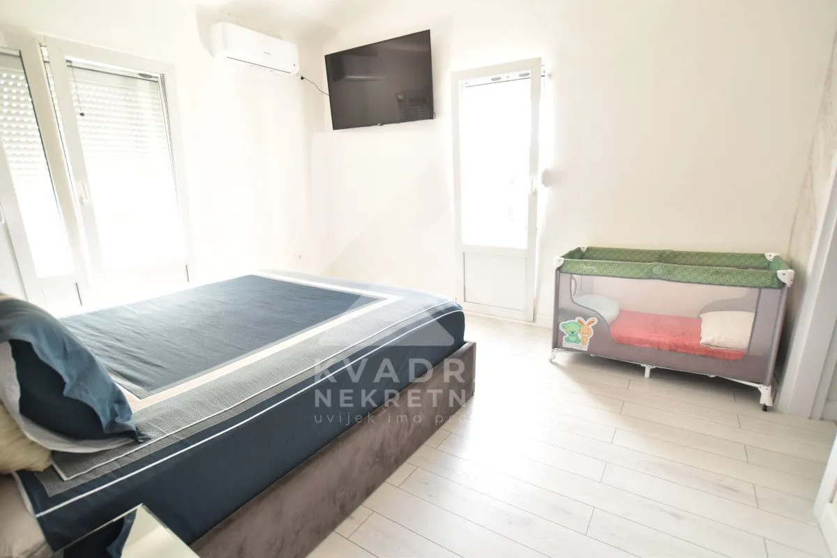 Bedroom with a double bed, air conditioning, TV, and a baby cot.