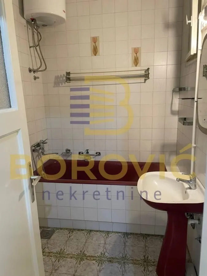 Small bathroom with a bathtub, washbasin, and tiled walls.