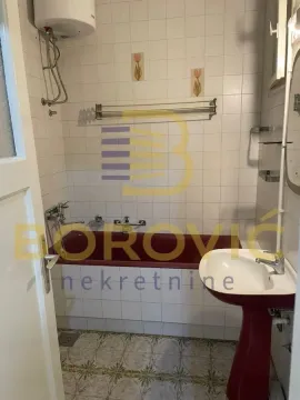 Small bathroom with a bathtub, washbasin, and tiled walls. - image 9