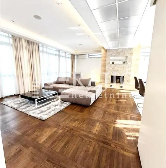 Spacious and bright living room with a sofa set and a stone-clad fireplace.