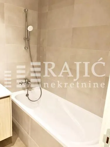 Modern bathroom with a bathtub and shower fixture tiled with ceramic tiles.