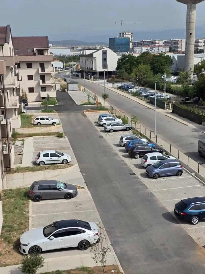 Pogled sa terase na parking i okolne stambene zgrade.