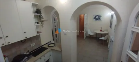 Small kitchen with white cabinets and a view of the dining area through arched openings. - image 9