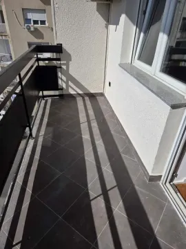 Manji popločani balkon sa crnom ogradom i pogledom na okolne zgrade. - image 8