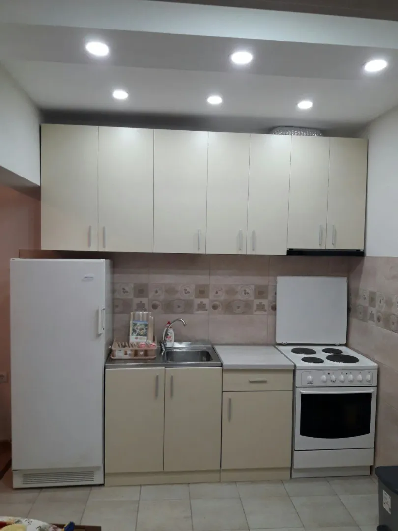 A simple kitchen with light-colored cabinets, a refrigerator, and a stove.