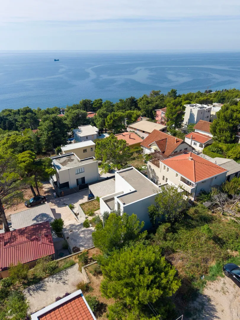 Pogled iz vazduha na kuće i naselje u blizini mora.