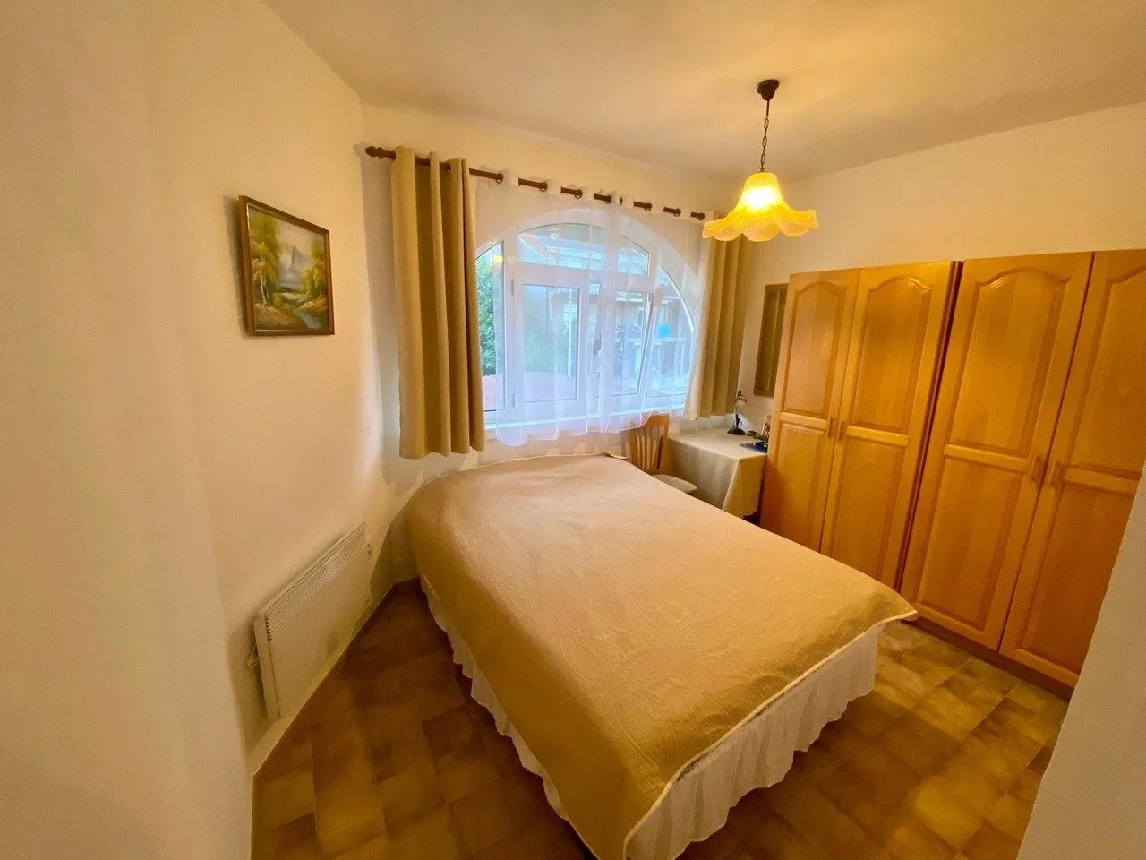 Namještena spavaća soba sa bračnim krevetom, velikim ormarom i prozorom.