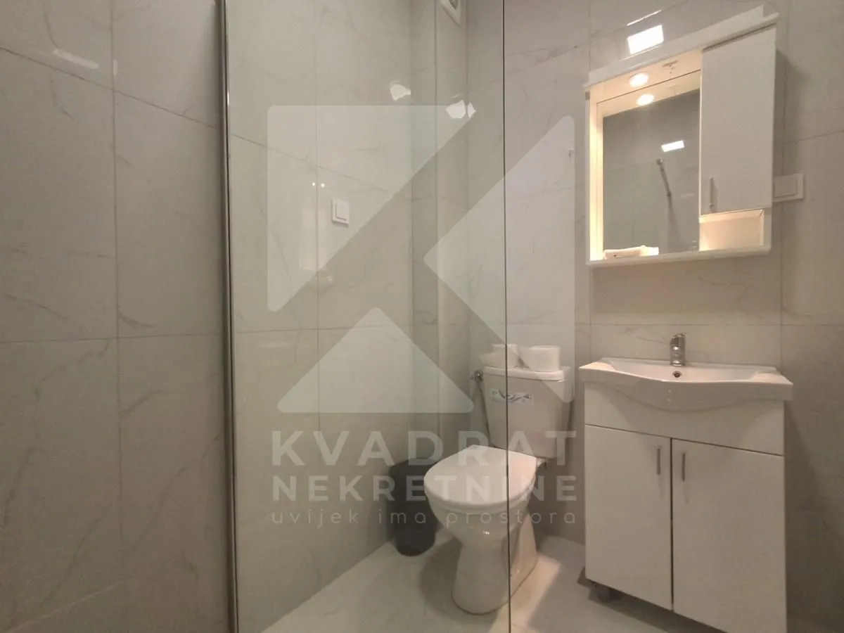 Modernly equipped bathroom with a shower cabin, washbasin, and toilet.