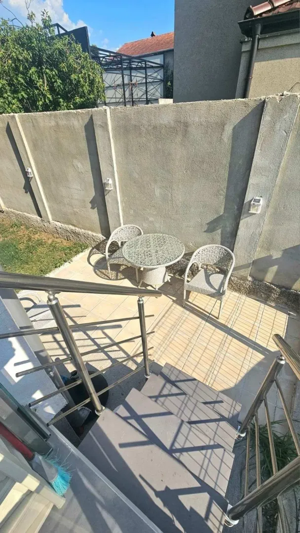 Popločani dio dvorišta sa garniturom za sjedenje i stepeništem.
