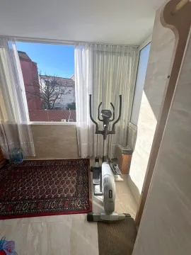 Zastakljena terasa sa trenažerom i pogledom na gradsko okruženje. - image 7