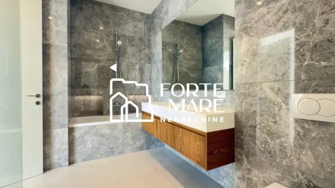 Modern bathroom lined with grey marble tiles featuring a bathtub and a wooden vanity unit with a washbasin. - image 9