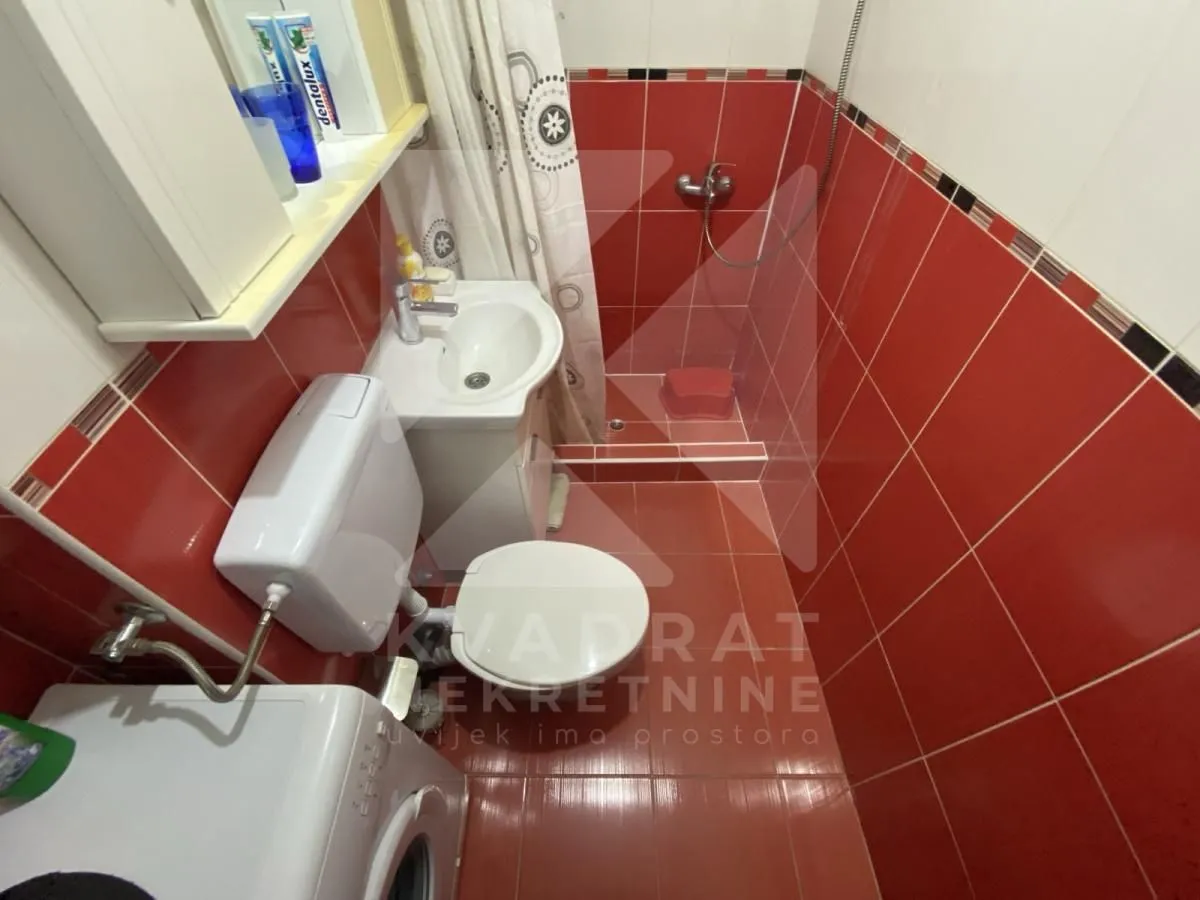 Bathroom with a shower cabin and red wall tiles.
