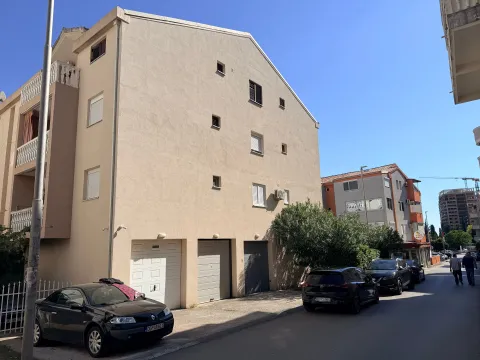 Pogled na spoljašnjost stambene zgrade sa garažama i ulicom. - image 2
