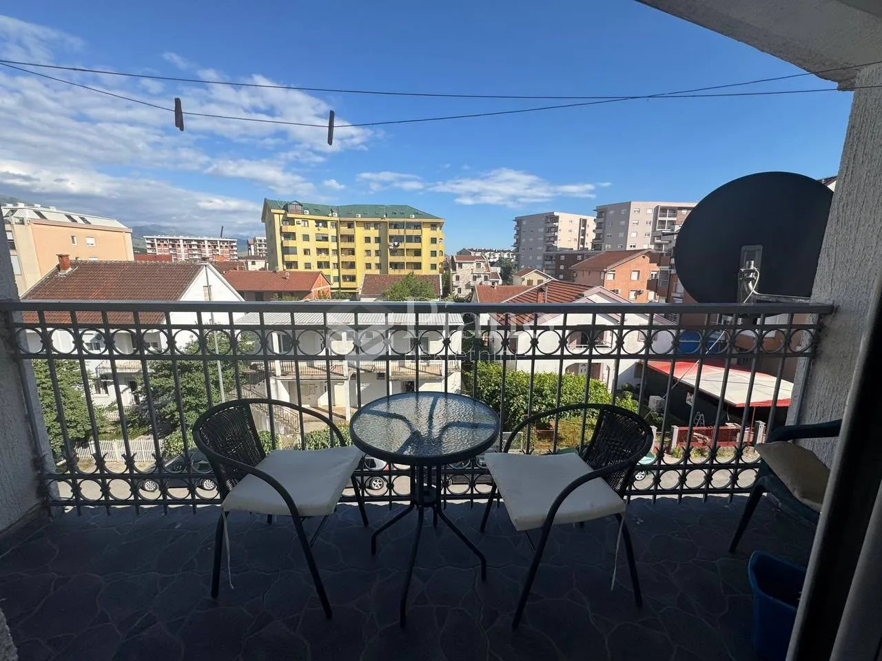 Namješten balkon sa stolom i dvije stolice i pogledom na grad.