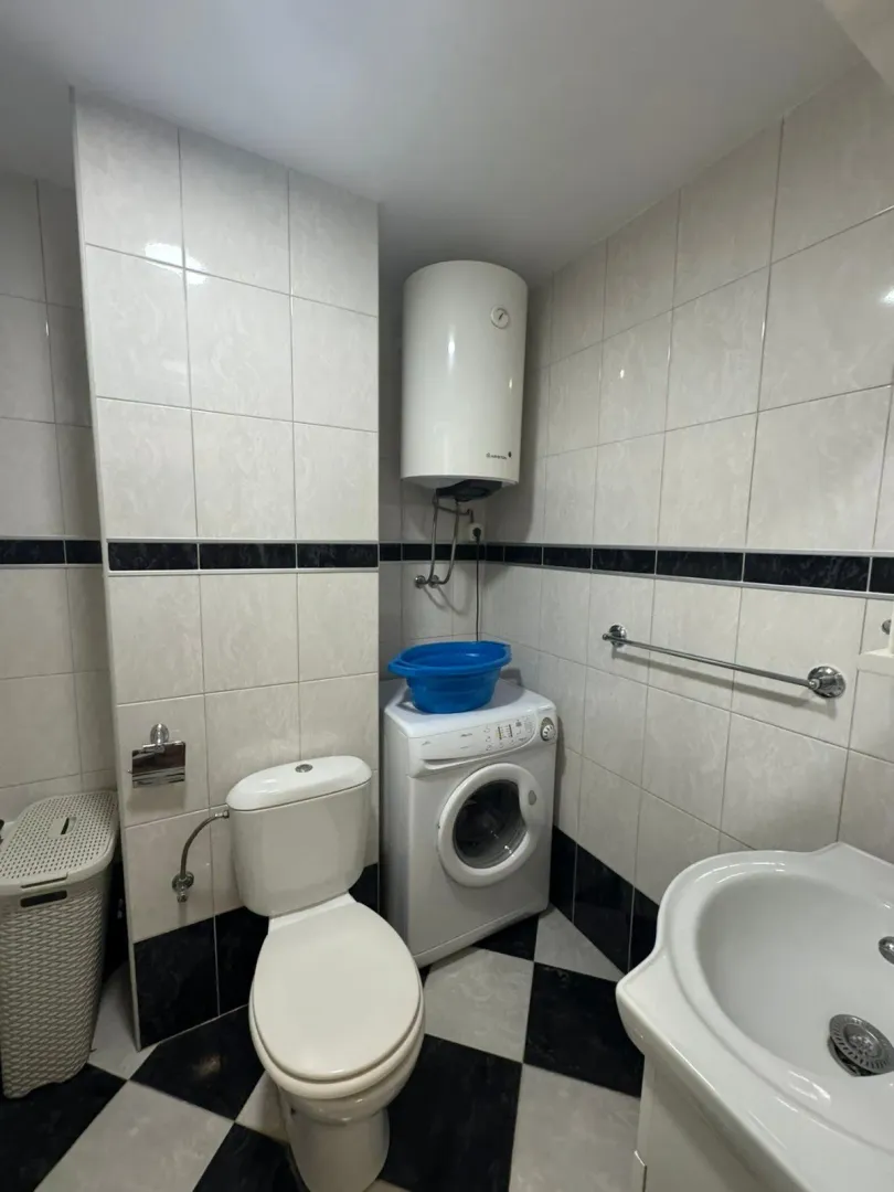 Bathroom equipped with a toilet, sink, washing machine, and water heater.
