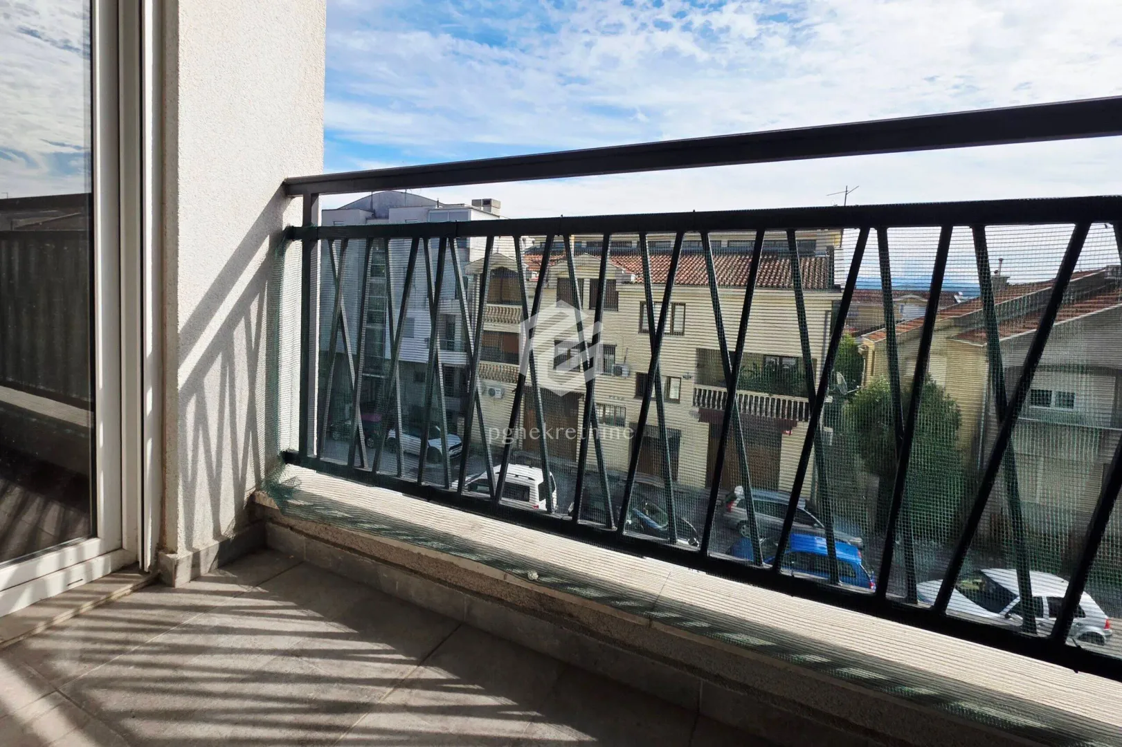 Small balcony with a metal railing and a street view.