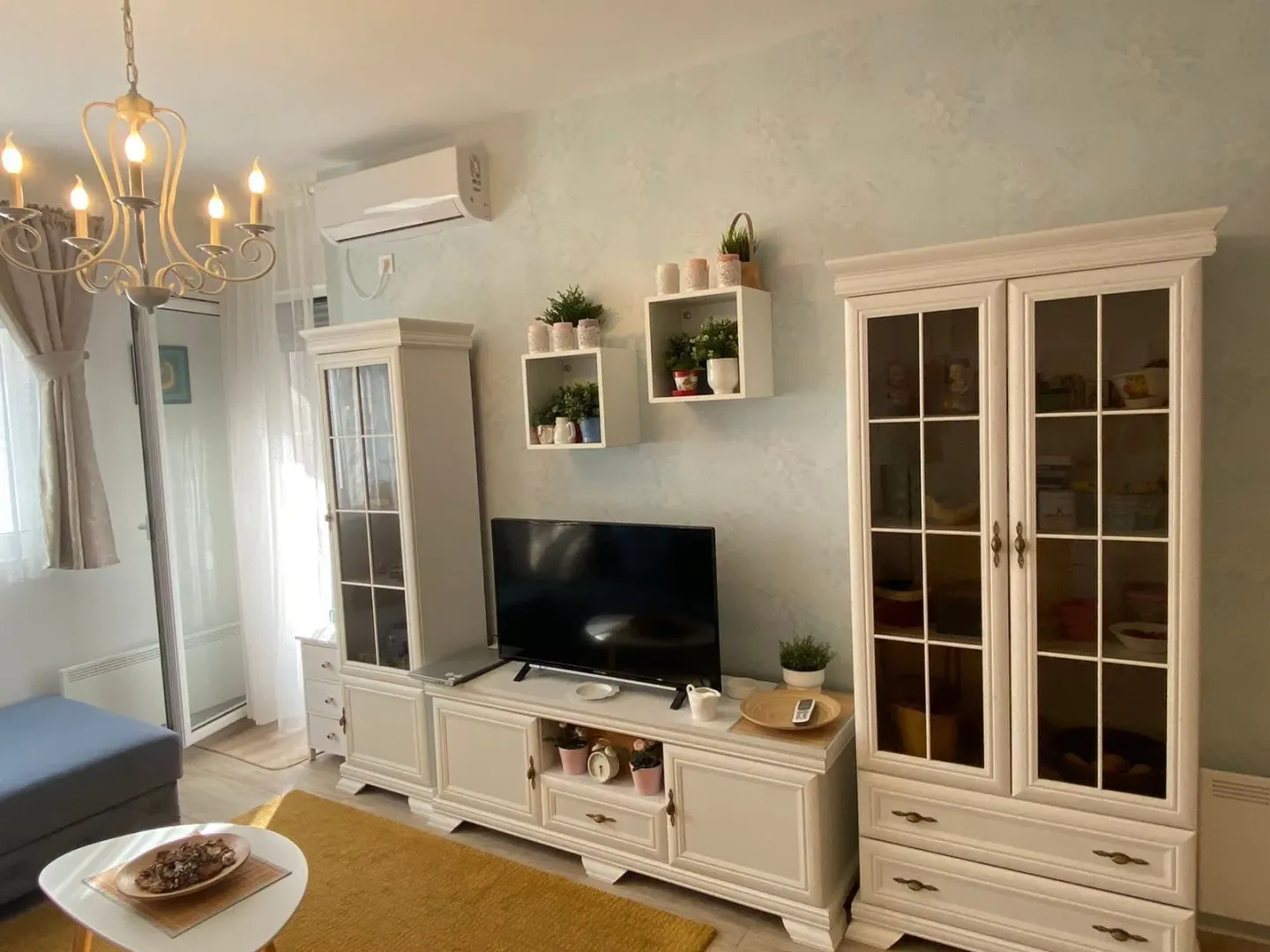 Living room with white furniture and a TV.