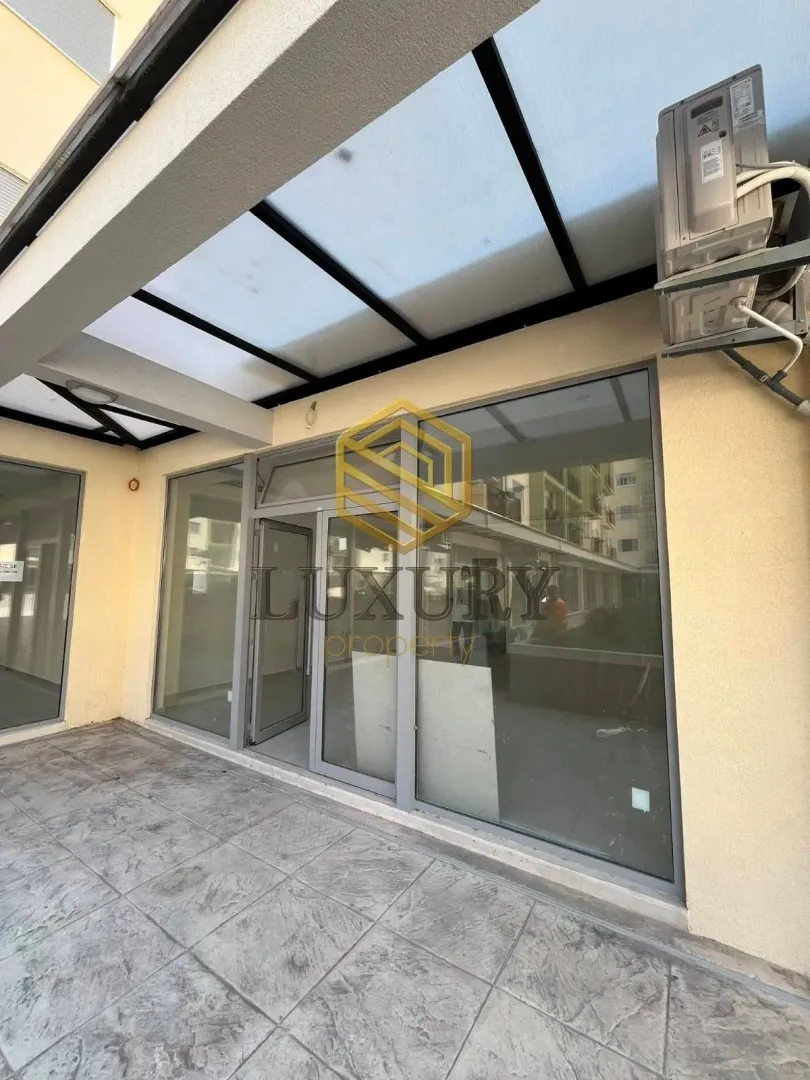 Exterior of a commercial space with a glass storefront and a covered terrace.