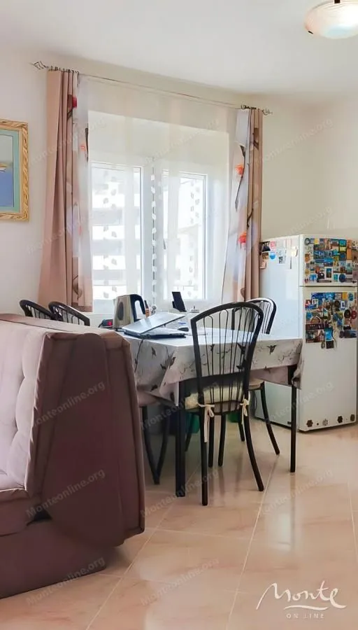 Dnevni boravak sa trpezarijskim stolom i frižiderom.