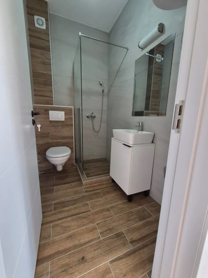 Moderno kupatilo sa tuš kabinom, umivaonikom i WC šoljom.