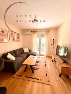 Uređena dnevna soba sa garniturom, TV-om i izlazom na terasu. - image 4