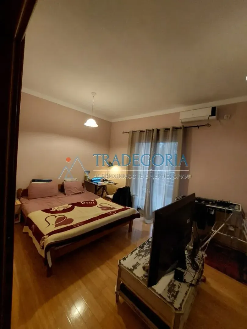 Spavaća soba sa bračnim krevetom, televizorom i izlazom na terasu.