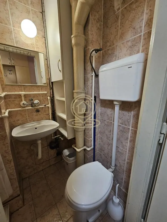 Manje kupatilo obloženo keramičkim pločicama sa umivaonikom i wc šoljom.