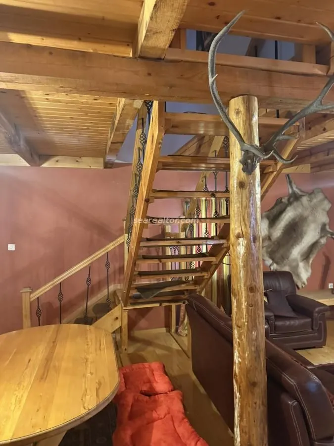 Dnevna soba sa drvenim stepeništem i rustičnim detaljima.