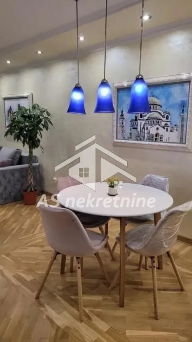 Trpezarijski deo sa okruglim stolom i modernim stolicama.