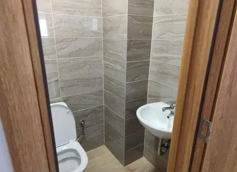 Small bathroom with tile finishes, a toilet, and a sink. - image 14
