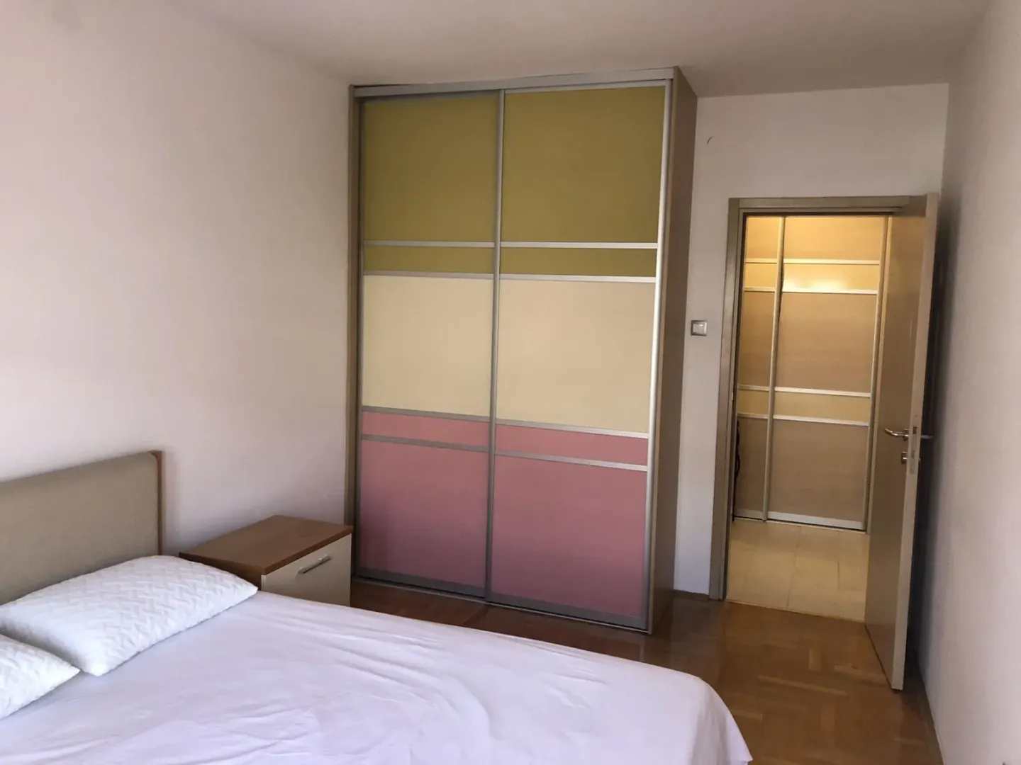 Bright bedroom with a built-in wardrobe and a nightstand.