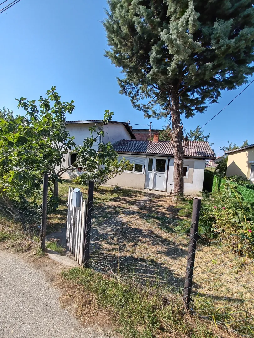Pogled na dvorište i fasadu kuće sa ogradom.