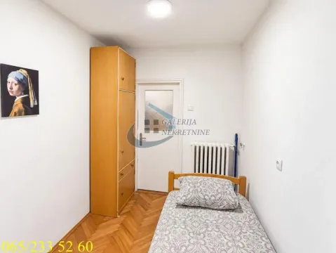 Manja spavaća soba sa krevetom, ormanom i parketom na podu. - image 7