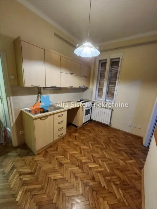 Small kitchen with light wooden cabinets and parquet flooring.