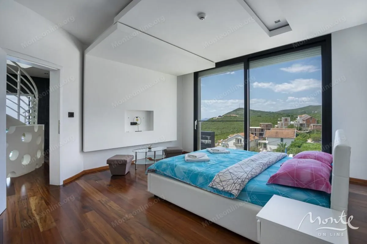 Bright bedroom with a double bed and large glass doors leading to a nature view.