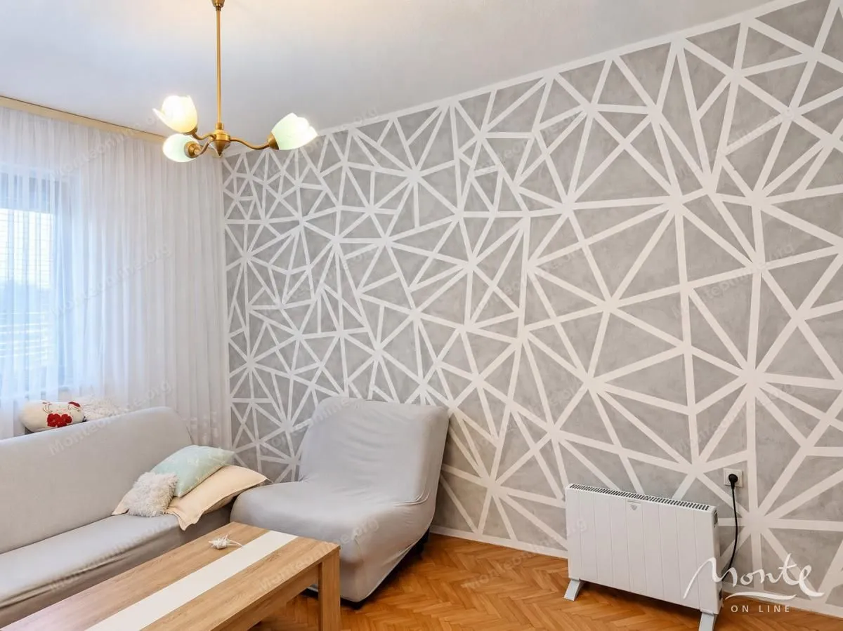 Dnevna soba sa garniturom i zidom ukrašenim geometrijskim šarama.