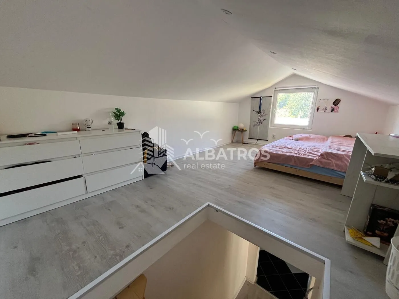 Attic space furnished as a bedroom with a bed and a dresser.