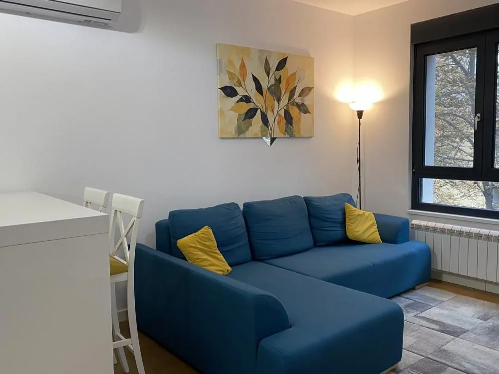 Living room with a blue sectional sofa and an artwork on the wall.