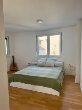 Spavaća soba sa bračnim krevetom, parketom i gitarom u uglu. - image 12