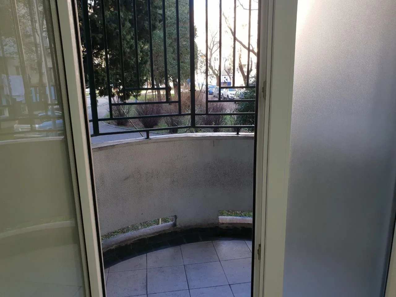 View of a small semi-circular balcony with a metal railing through an open balcony door.