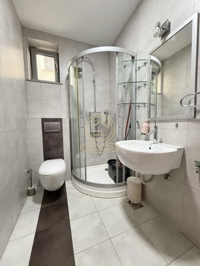 Bathroom equipped with a shower cabin, washbasin, toilet, and mirror.