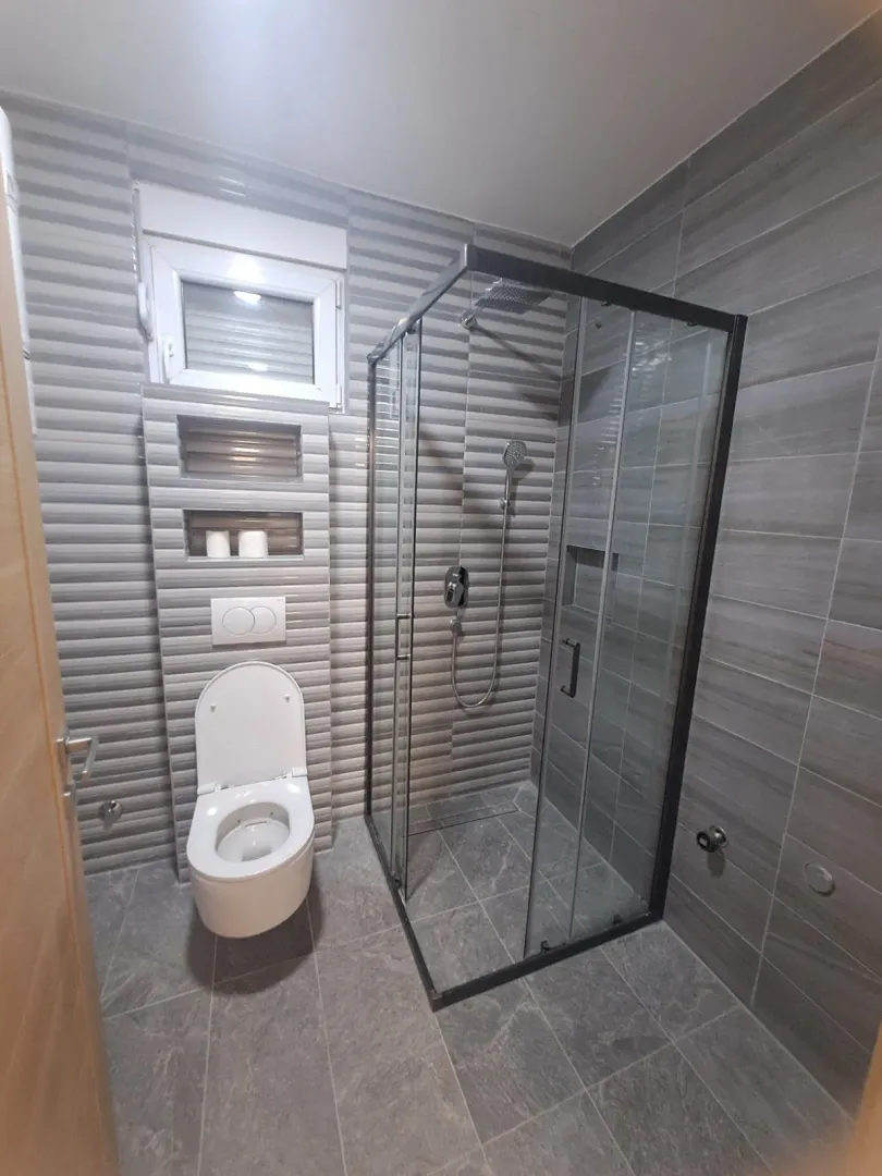 Modernly equipped bathroom with a shower cabin and a wall-hung toilet.