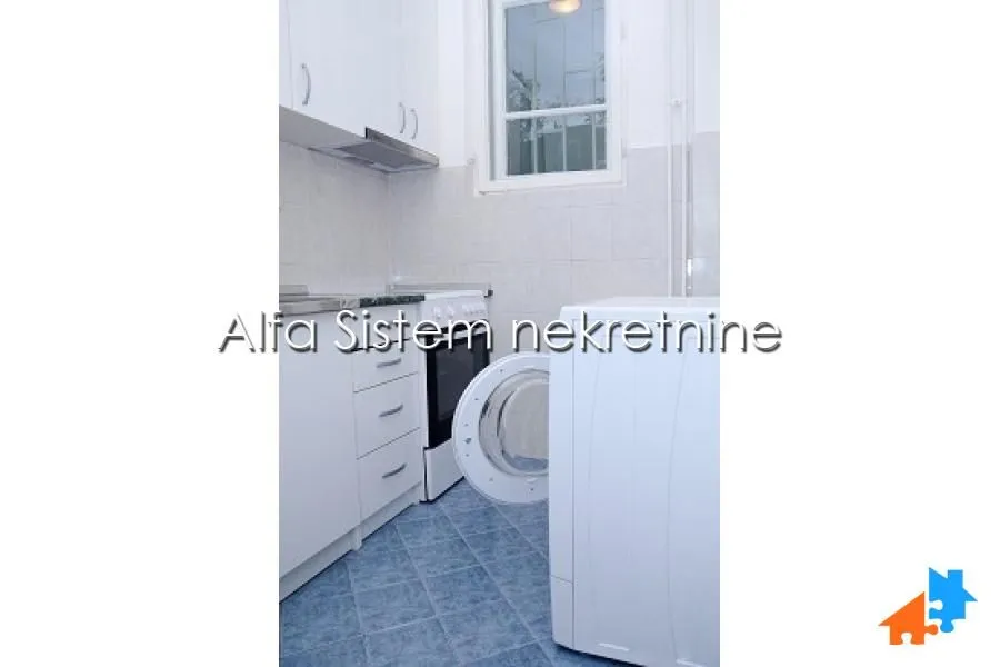 Small white kitchen with a stove and a washing machine.