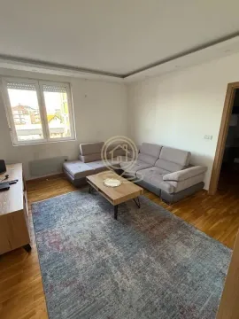 Dnevna soba sa garniturom, stočićem i prozorom koji gleda na okolne zgrade. - image 2